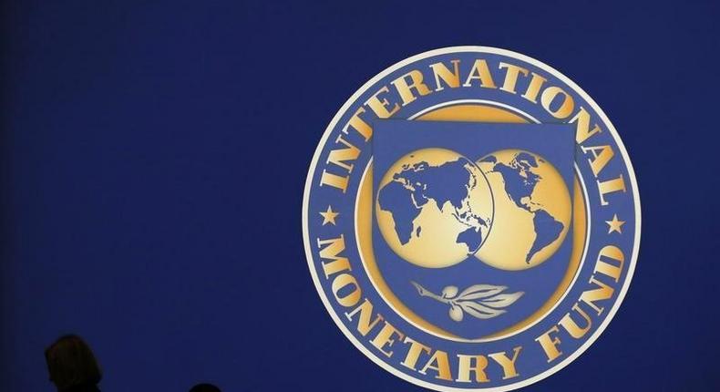 Visitors are silhouetted against the logo of the International Monetary Fund at the main venue for the IMF and World Bank annual meeting in Tokyo October 10, 2012. REUTERS/Kim Kyung-Hoon