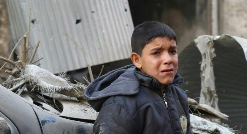 A Syrian boy cries as he stands next to a building hit by an air strike on the village of Maaret al-Numan, in the country's northern province of Idlib, on December 4, 2016