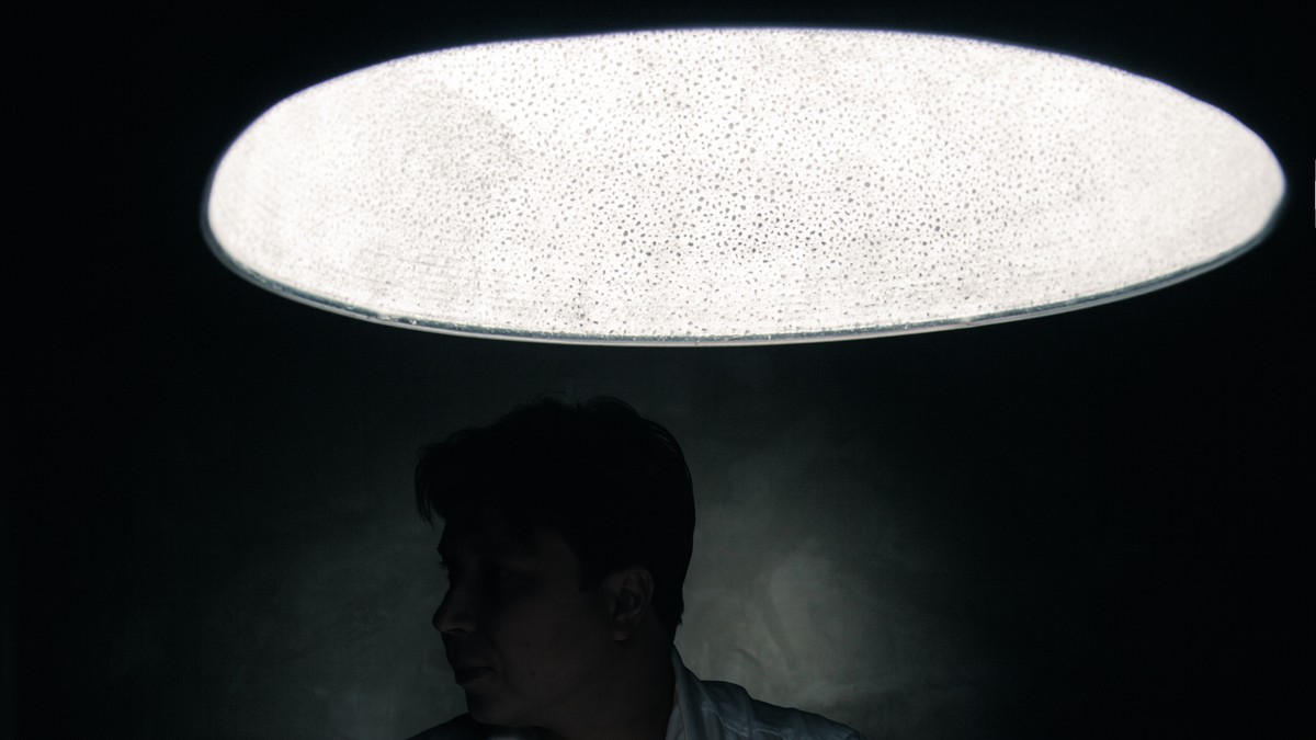 stock-photo-man-in-a-dark-room-illuminated-only-by-a-light-coming-from-a-lamp-no-face-seen-250644610