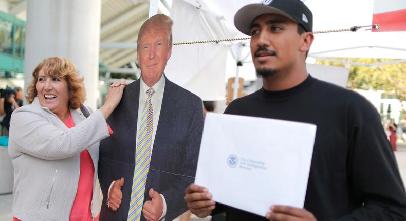 New U.S. citizens pose with a cardboard cutout of U.S. President Donald Trump after a naturalization ceremony for new U.S. citizens in Los Angeles.