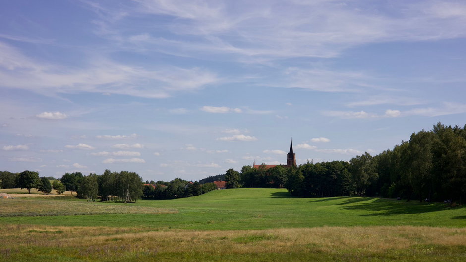 Z rozległych łąk na Łyną, spośród malowniczych pagórków wystrzela w niebo ostra wieża kościoła w Brąswałdzie
