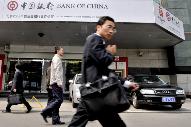 Pracownik umysłowy na tle oddziału Bank of China w Pekinie. Fot. Bloomberg