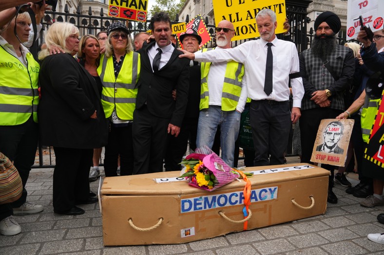 Protest przeciwko rozszerzeniu ULEZ, jego uczestnicy przynieśli atrapę trumny z tektury z napisem "DEMOKRACJA", Londyn, 29 sierpnia 2023 r.