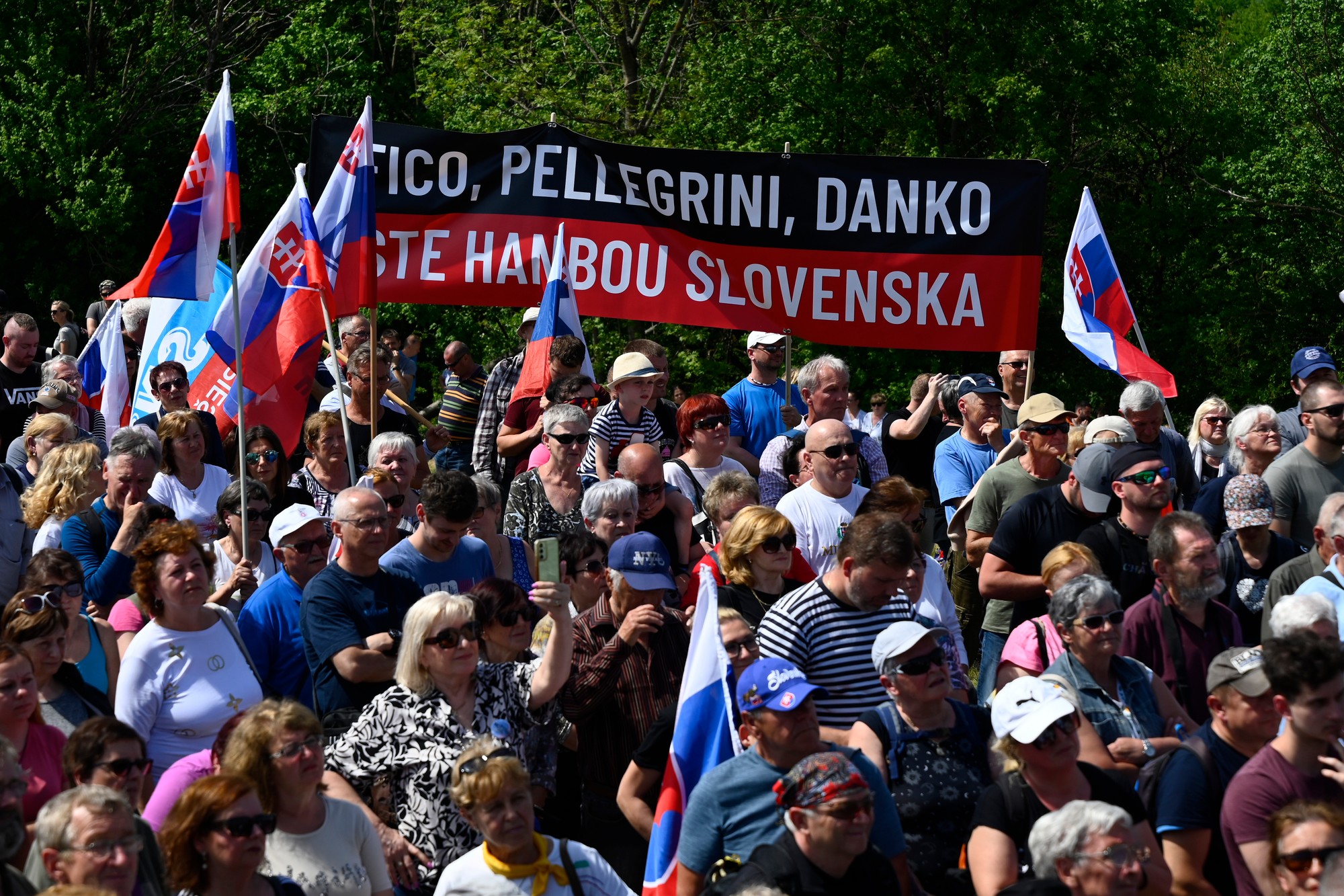 Ľudia držia slovenské vlajky a transparent na spomienkovom podujatí pri príležitostí 105. výročia tragickej smrti generála Milana Rastislava Štefánika.
