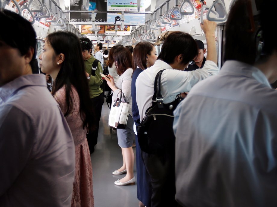 Commuters check their phones inside a train in Tokyo.