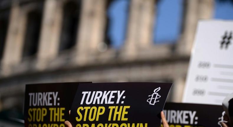 Amnesty International activists hold placards as they protest against the arrest of rights activists in Turkey, including Amnesty International's Turkey director, on July 20, 2017, near the Coliseum in Rome