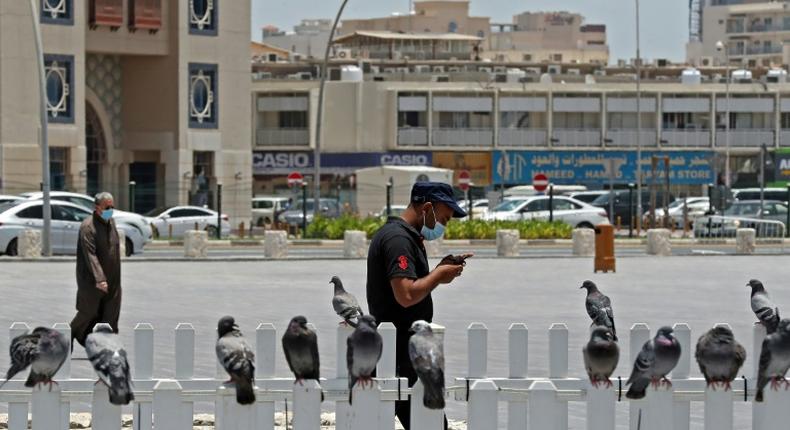 A masked man checks his phone in Qatar where residents and citizens have been required by law to install a coronavirus contact tracing app on their handsets since Friday