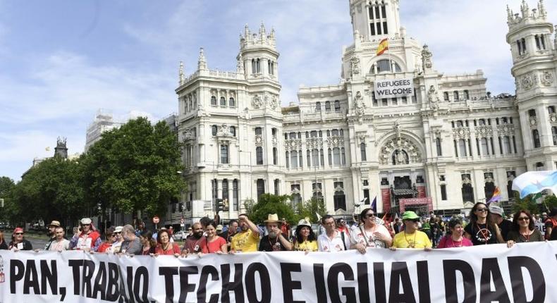 People hold a banner that reads Bread, work, roof and equality during a demonstration in Madrid on May 27, 2017 to denounce degraded working conditions