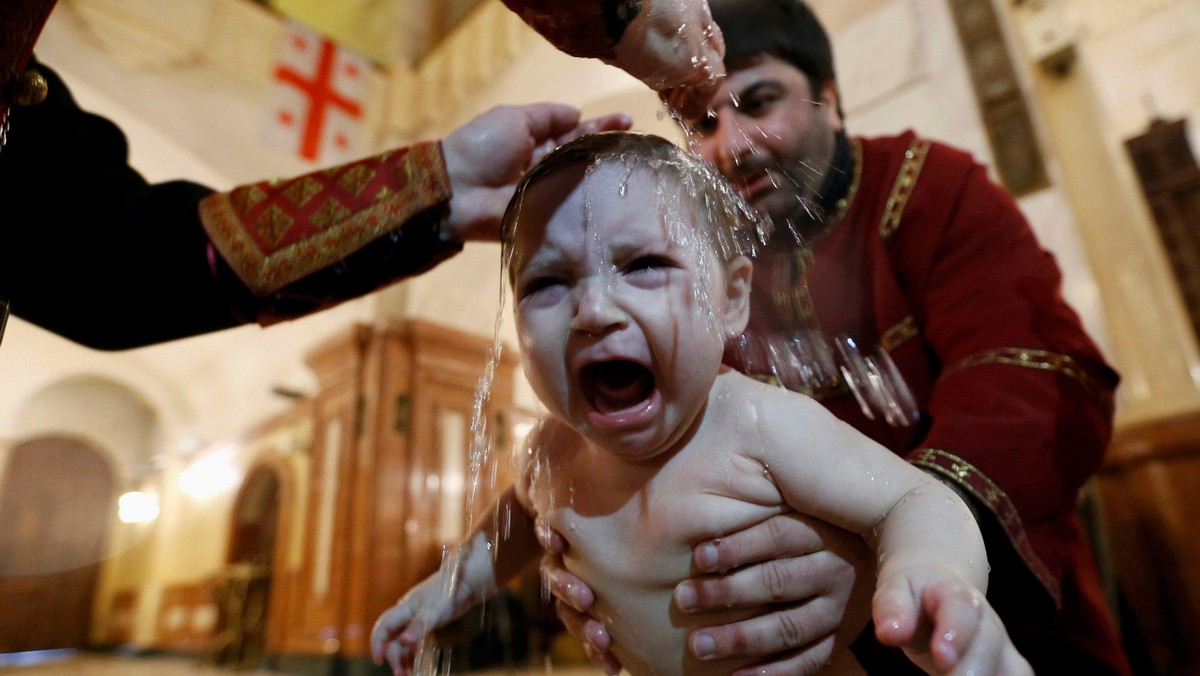 Baby is baptised during mass baptism ceremony on Orthodox Epiphany Day at Holy Trinity Cathedral in 