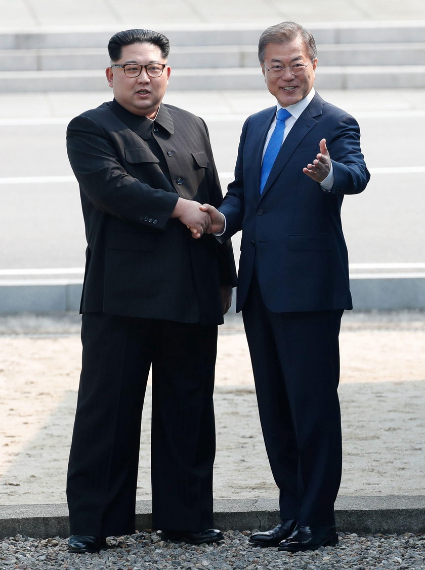 Security personnel run alongside the vehicle carrying North Korean leader Kim Jong Un at the truce v