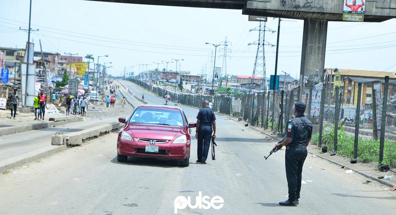 Nigerian police officers stop a car at a checkpoint in Mile 12 (Pulse)