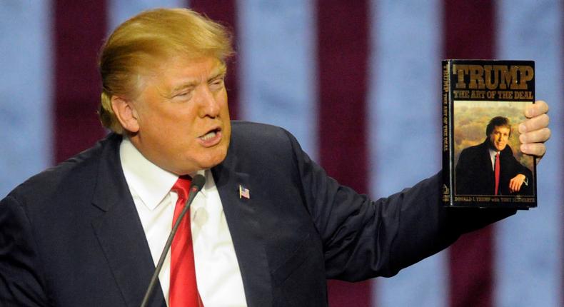 President Donald Trump holds up his book The Art of the Deal during a presidential campaign stop in November 2015.