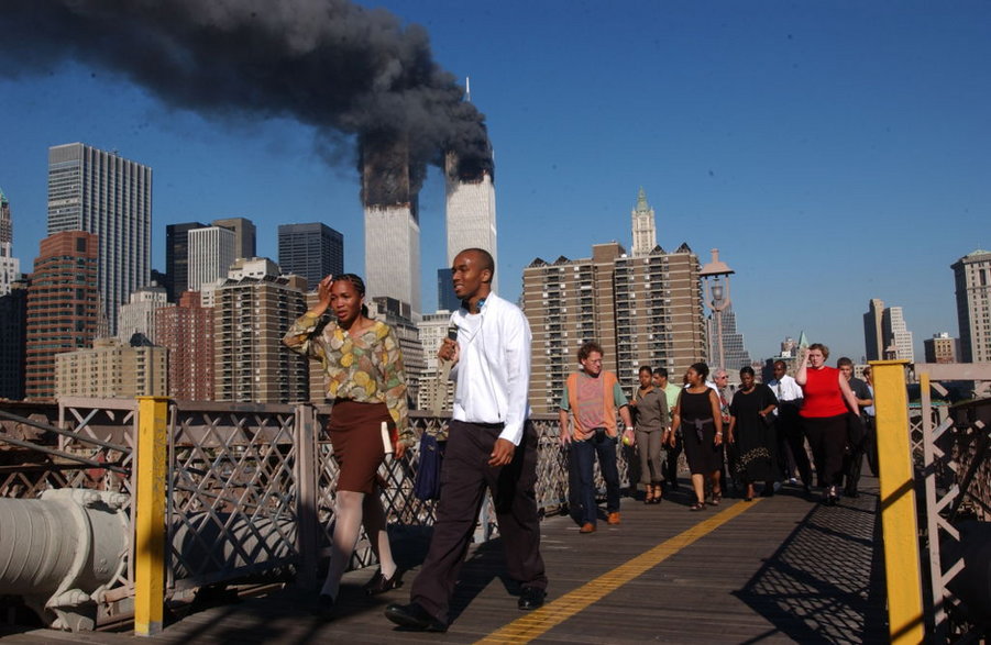 Mieszkańcy Nowego Jorku na Moście Brooklińskim, w tle płonące wieże WTC po zamachu 11 września 2001 r.