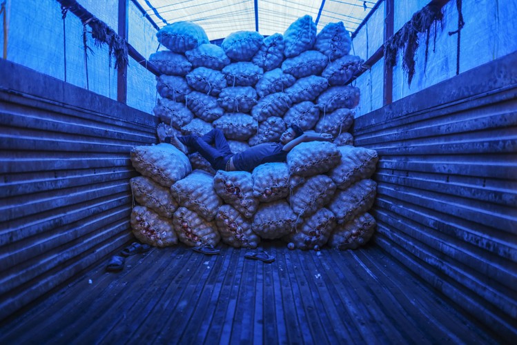 Giełda owoców i warzyw w Bombaju w Indiach. Robotnik ucina sobie drzemkę w ciężarówce na stosie worków w cebulą.