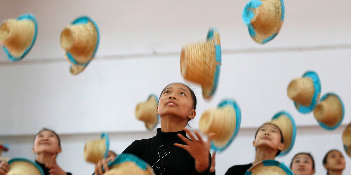 Girls juggle with straw hats at an acrobatics school in Huzhou, Zhejiang province, November 14, 2013. According to a spokesperson from the school, 32 children, whose parents are low-wage migrant workers in the city, are exempted from tuition fees and other costs. The students of the school receive five-hour acrobatic and dance training during the day, and two-hour literacy courses in the evening.