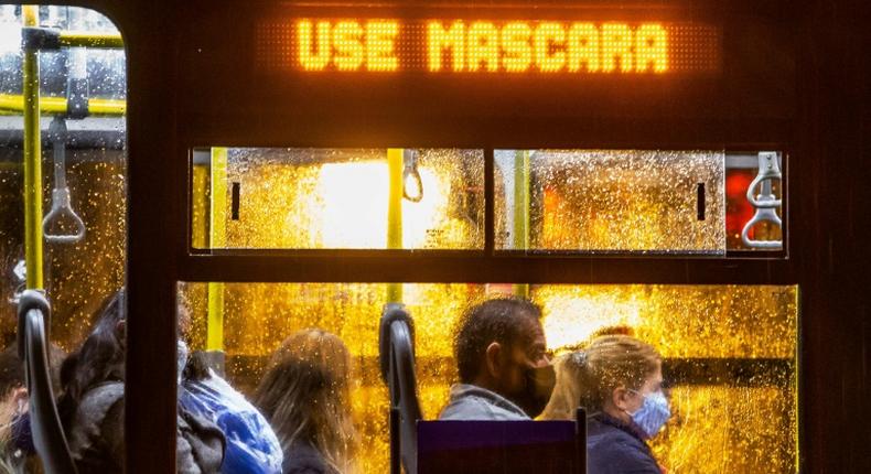 Commuters wearing face masks travel on a public bus with an electronic sign reading Wear a face mask, in Curitiba, Brazil on May 22, 2020