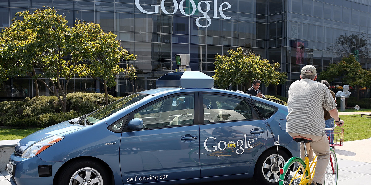 A cyclist passes an early Google self-driving car in 2012