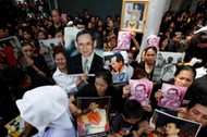 People hold portraits of Thailand's late King Bhumibol Adulyadejas as they wait on the roadside whil