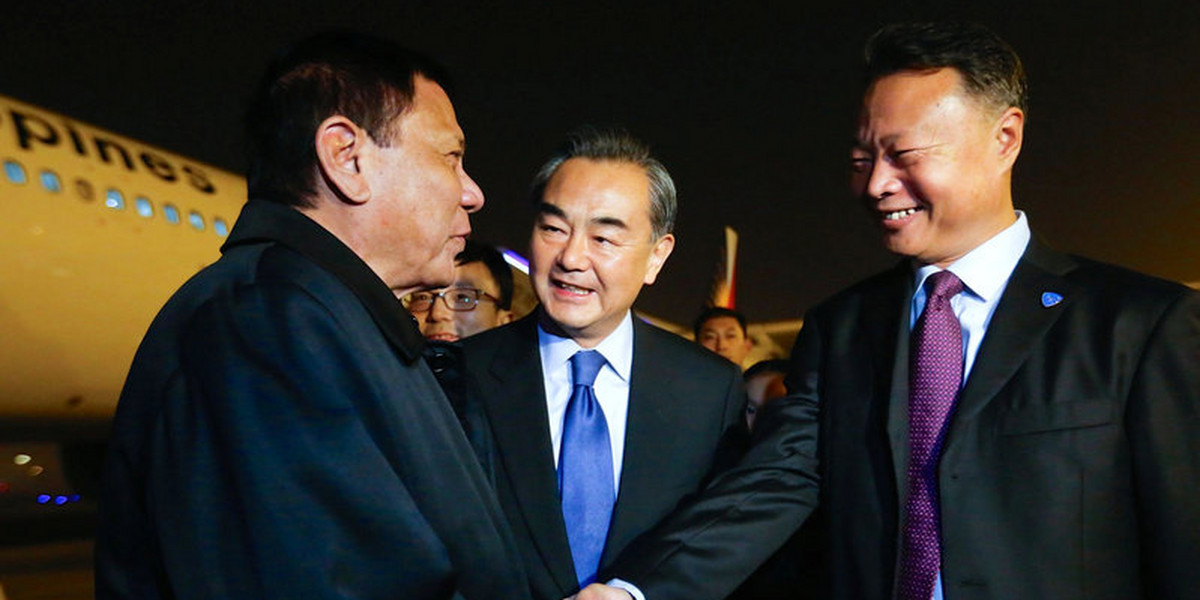 Philippine President Rodrigo Duterte shakes hands with Chinese ambassador to the Philippines Zhao Jianhua, as Chinese Foreign Minister Wang Yi looks on, at airport in Beijing.