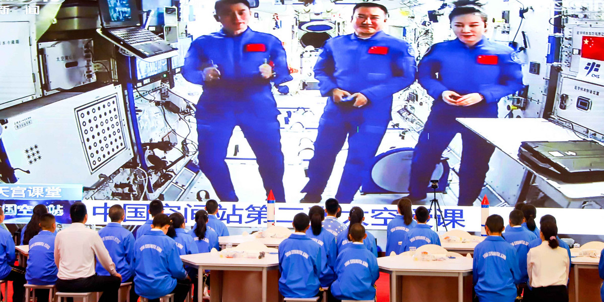 Uczniowie słuchają wykładu nagranego przez załogę chińskiej stacji kosmicznej Tiangong, marzec 2022 r.