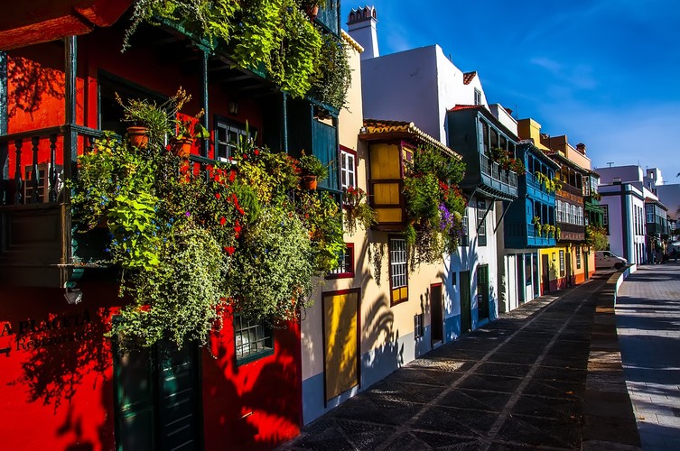 <strong>La Palma – dla lubiących wypoczynek w karaibskim stylu</strong>
<br></br>
Znana jako La Isla Bonita, La Palma jest uważana za jedną z najładniejszych Wysp Kanaryjskich. W odróżnieniu od stonowanych Lanzarote czy Fuerteventury, tutaj królują kolory. Fasady budynków pomalowane są w wesołe barwy, a dookoła zielone plantacje bananów – trudno wyzbyć się wrażenia, że znaleźliśmy się w miejscu o wiele bardziej egzotycznym, niż hiszpańska wyspa. Wszystkie skojarzenia z środkowo i południowoamerykańskimi krajami dodatkowo umocni powszechny w La Palma zwyczaj ręcznego zwijania cygar. 
<br></br>
Na La Palma szybko zrozumiemy, dlaczego Wyspy Kanaryjskie nazywane są Wyspami Szczęśliwymi. Idylliczne, kolonialne miasteczka, w których czas biegnie własnym, niespiesznym tempem, uśmiechnięci mieszkańcy i ulice tętniące życiem – naprawdę czuć tu karaibski klimat. W dodatku cudowna przyroda wyspy – głębokie wąwozy porośnięte zielonym, wawrzynowym lasem, Caldera de Taburiente w której znajduje się Park Narodowy, niesamowite wodne tunele w Marcos y Cordero – po prostu szczęśliwy wypoczynek.
<br></br>
<a  href=