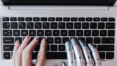 Robot and human hands share a keyboard.sompong_tom/Getty Images