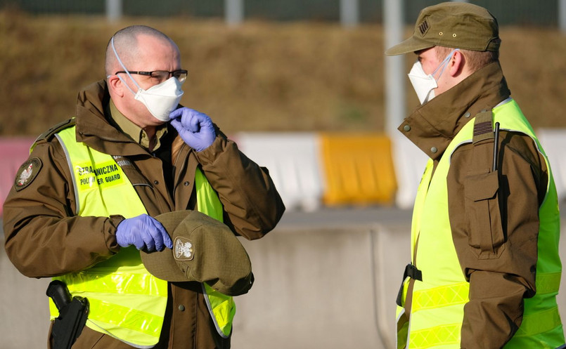 Funkcjonariusze służb granicznych podczas kontroli sanitarnej pasażerów autobusów wjeżdzających do Polski