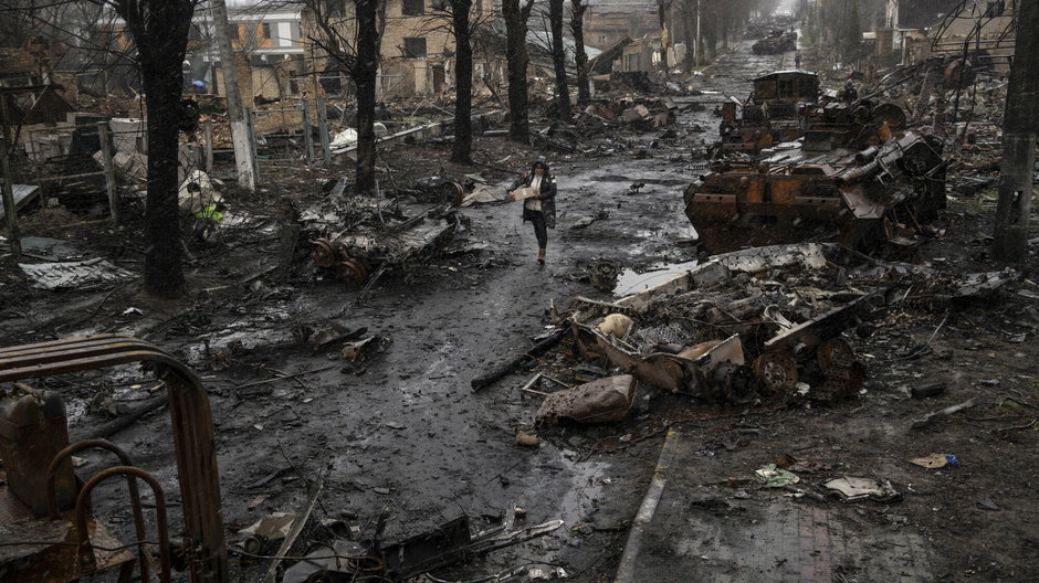 Kobieta spaceruje wśród zniszczonych rosyjskich czołgów w Buczy na obrzeżach Kijowa
