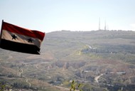 A Syrian national flag flutters as Qasioun mountain is seen in the background from Damascus