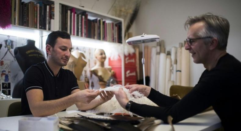 Serkan Cura, left, one of the world's top plumassiers, examines a feather design with Olivier Portais of the French wedding dress label Cymbeline