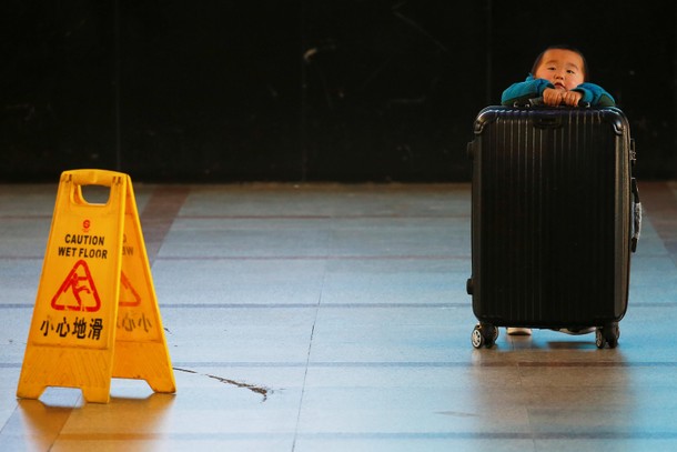 A boy tries to lift a suitcase at the departure hall of the Beijing Railway Station in central Beiji