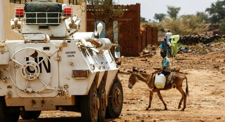 A Sudanese boy rides a donkey past an armoured vehicle of a UN-African Union mission in the war-torn town of Golo in central Darfur on June 19, 2017