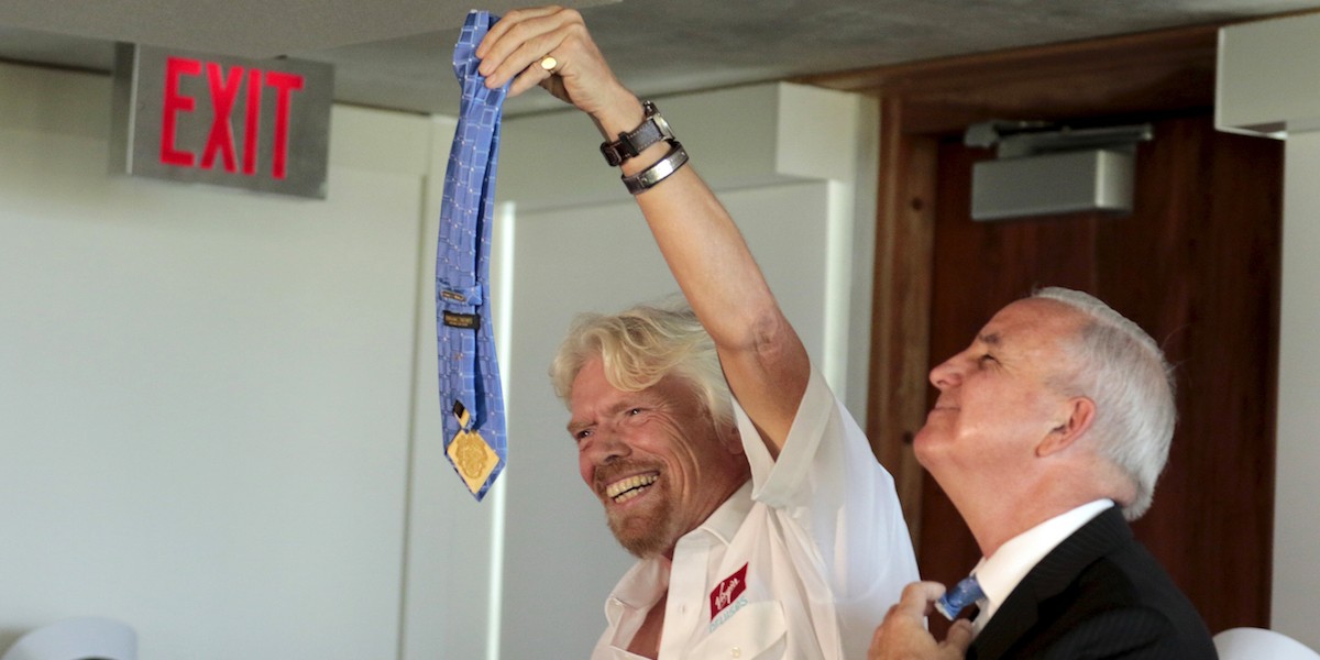 Virgin Group founder Richard Branson holds the tie he cut off Miami-Dade county Mayor Carlos A. Gimenez in 2015.