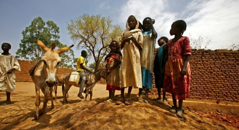 Sudanese women and children stand next to a donkey in the war-torn town of Golo in the thickly forested mountainous area of Jebel Marra in central Darfur on June 19, 2017