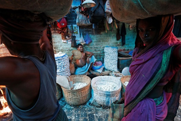 A vendor fans himself as he waits for customers at a wholesale vegetable market on a hot summer day 