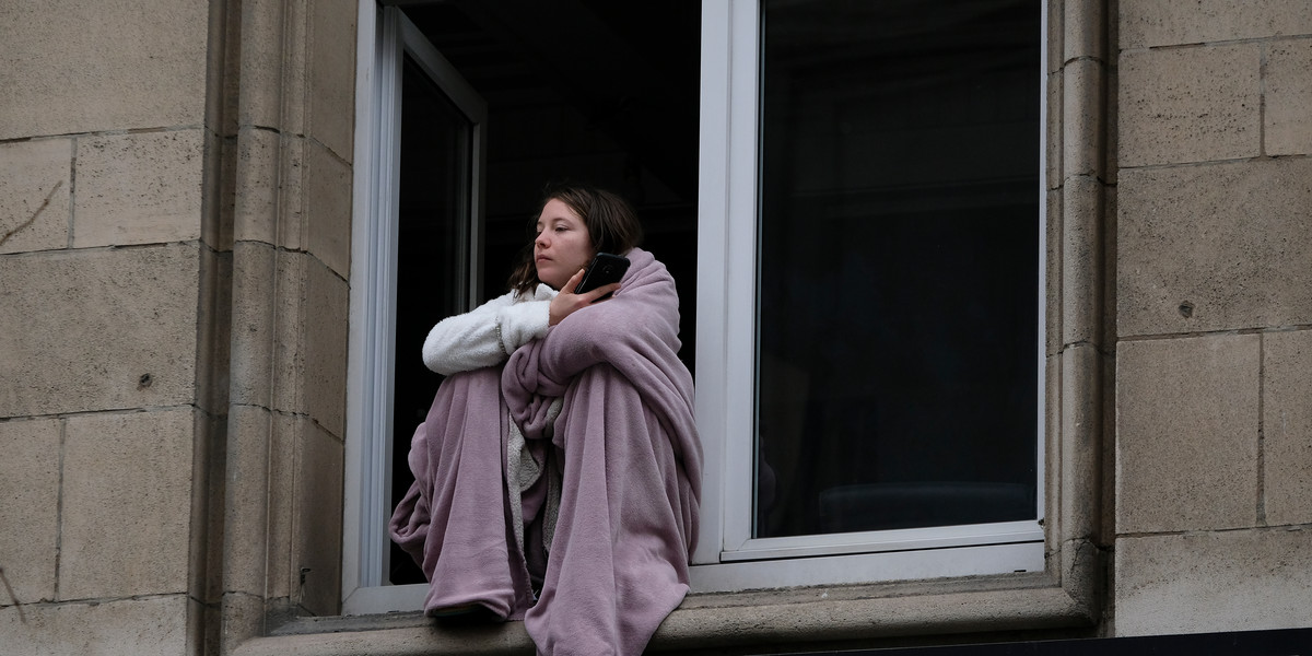Podczas pierwszego lockdownu w Europie, w marcu 2020 r., okna i balkony były substytutem wolności. Na zdjęciu młoda kobieta w oknie mieszkania w Brukseli.