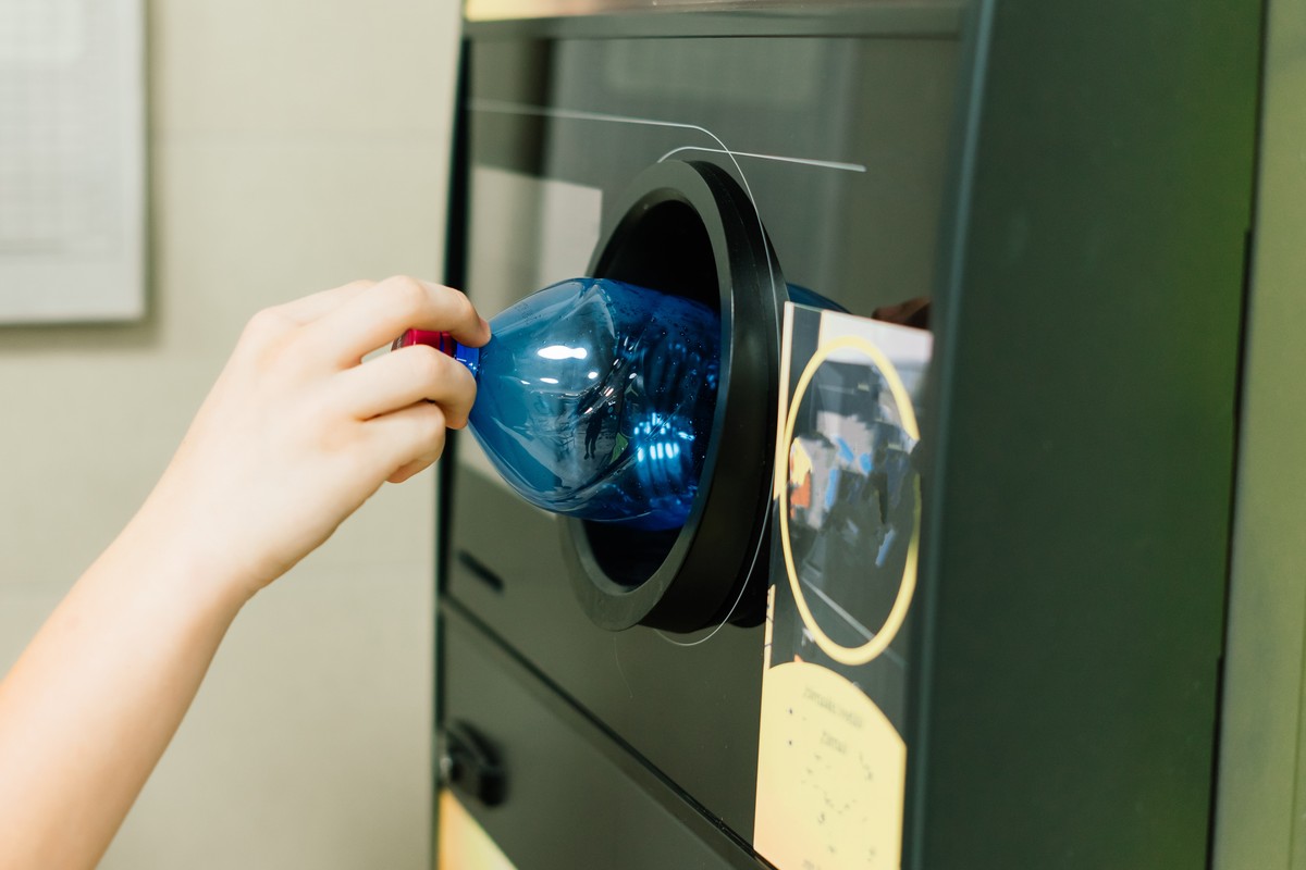 Osoba wkłada plastikową butelkę do automatu zwrotu opakowań w systemie kaucyjnym