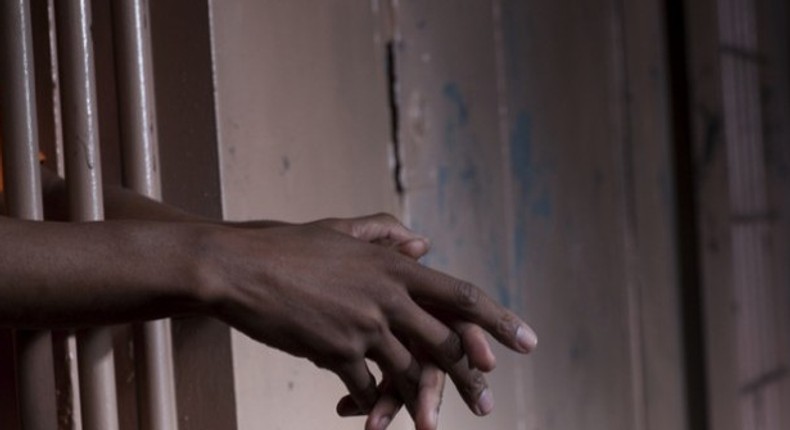 Hands gripping the bars of a jail cell