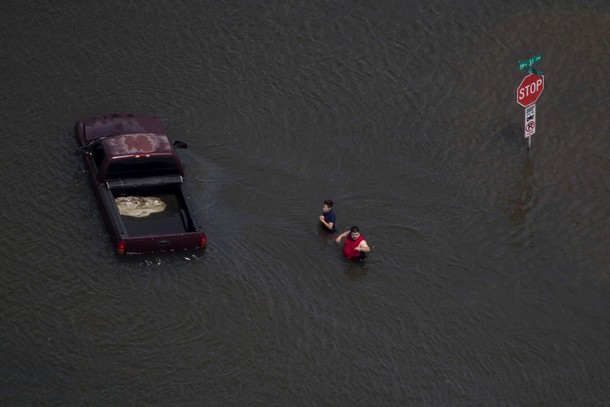 A woman holds her hands as she and a man stand submerged in flood waters caused by Tropical Storm Ha