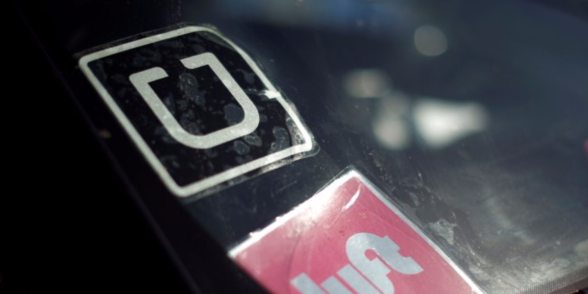 A driver displaying Uber and Lyft signs on his car in Santa Monica, California.