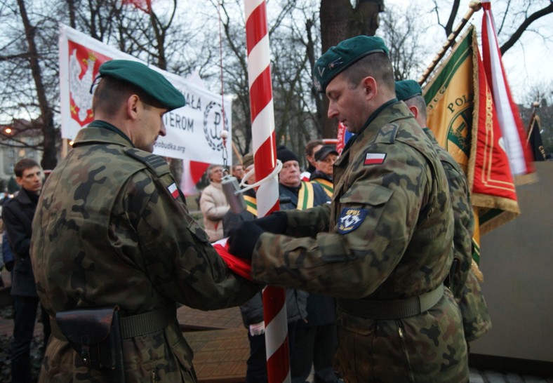 Żołnierze wieszają flagę Polski na maszt