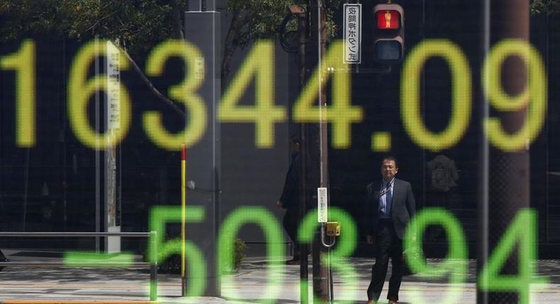 A businessman is reflected in an electronic board displaying Japan's Nikkei share average outside a brokerage in Tokyo, Japan, April 18, 2016. 