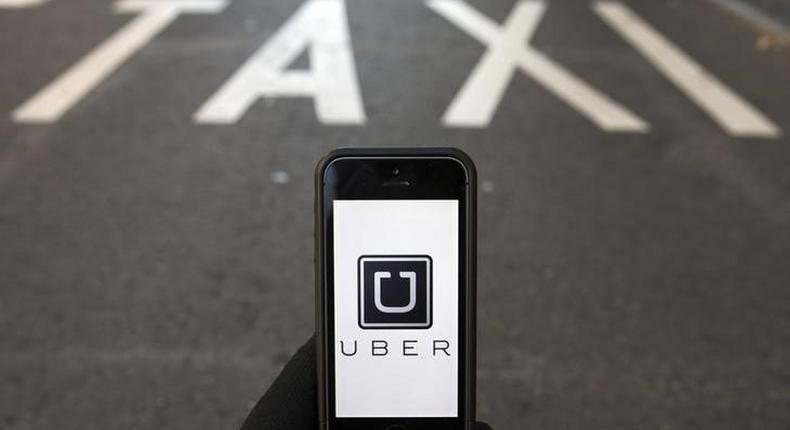 The logo of car-sharing service app Uber on a smartphone over a reserved lane for taxis in a street is seen in this photo illustration taken in Madrid on December 10, 2014. REUTERS/Sergio Perez