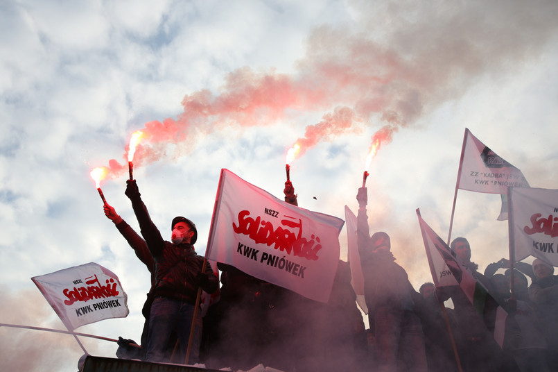 Górnicy nie chcą oddać przywilejów Na początku roku władze JSW, borykające się z problemami finansowymi spółki, ogłosiły plan naprawczy i ostrzegły, że zarząd jest zmuszony między innymi do zamrożenia płac w 2015 r., zmniejszenia deputatu węglowego, rezygnacji z dopłat do zwolnień lekarskich oraz uzależnienia wypłaty czternastej pensji od zysku firmy (miała być wypłacana w tym roku w ratach). Ponadto zarząd chciałby płacić za pracę w soboty i niedziele zgodnie z Kodeksem pracy, a nie - jak obecnie - z korzystniejszymi dla pracowników regulacjami wewnętrznymi. W odpowiedzi górniczy związkowcy ogłosili akcję protestacyjno-strajkową - od 28 stycznia trwa bezterminowy strajk w kopalniach JSW, przybierający nieraz ostrą formę. >>Patrz: Przed siedzibą JSW policja użyła broni gładkolufowej Górnicy nie godzą się na wypowiedzenie trzech punktów układu zbiorowego, domagają się też odwołania prezesa spółki. Rząd, który pośredniczy w rozmowach zarządu ze związkowcami, nie ugina się jednak pod presją górników. Ewa Kopacz przypomniała, że państwo nie jest jedynym właścicielem spółki JSW, ma bowiem 51 procent udziałów, liczą się więc także mniejszościowi udziałowcy. >>Czytaj też: Solidarnościowy protest w wydaniu delikatnym: poparcie dla górników z JSW tylko słowne