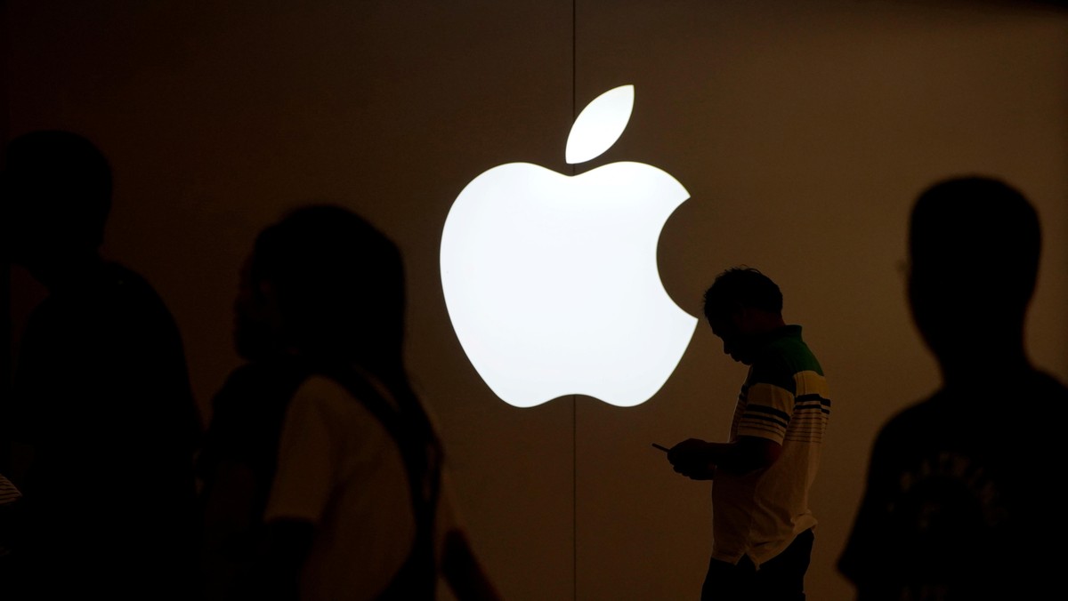 FILE PHOTO: A man looks at the screen of his mobile phone in front of an Apple logo outside its store in Shanghai