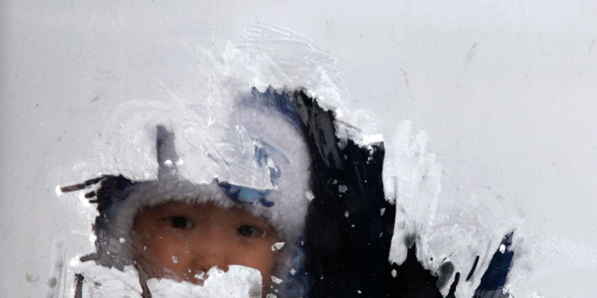 A child looks through a bus window covered by frost in Ulan Bator, December 27, 2013.
