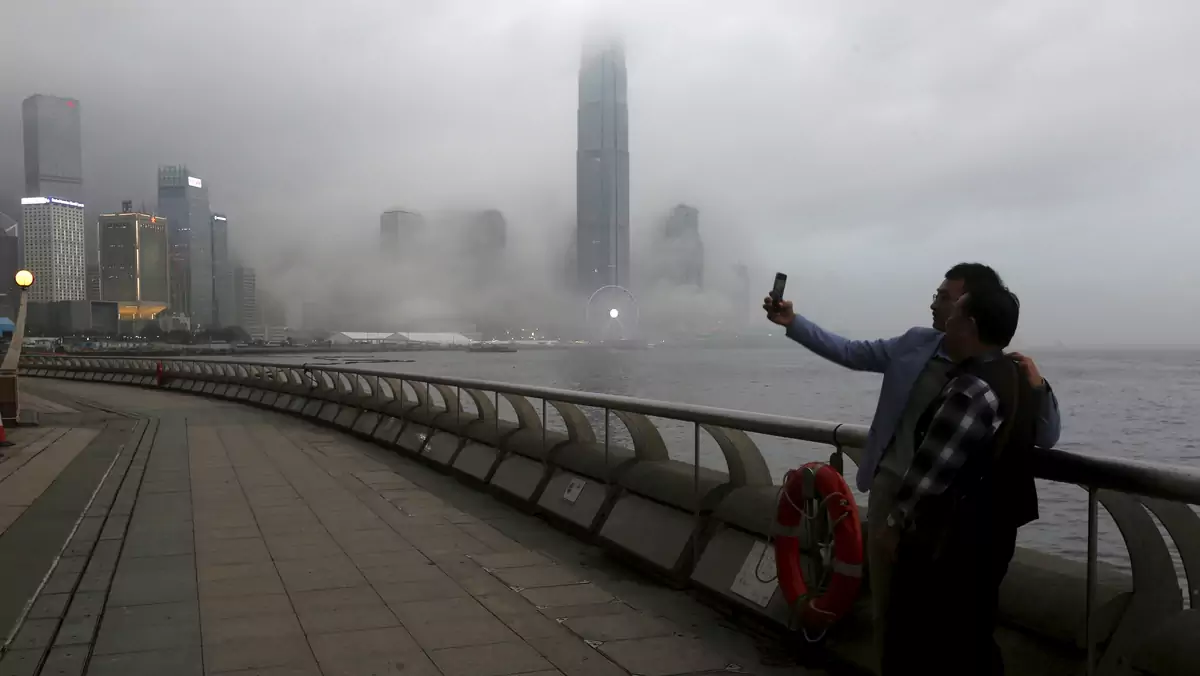 People take a selfie in front of the financial Central district under foggy weather in Hong Kong