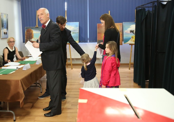 Kandydat ugrupowania KORWiN - Janusz Korwin-Mikke (L), głosuje w lokalu wyborczym w Józefowie pod Warszawą. Obok córka Zuzanna z dziećmi i mężem Maciejem Dębalą