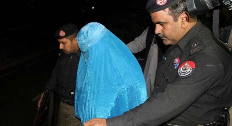 Pakistani policemen escort Afghan refugee woman Sharbat Gula (C) as she leaves the Lady Reading Hospital where she was treated, in Peshawar on November 9, 2016, before her deportation to Afghanistan