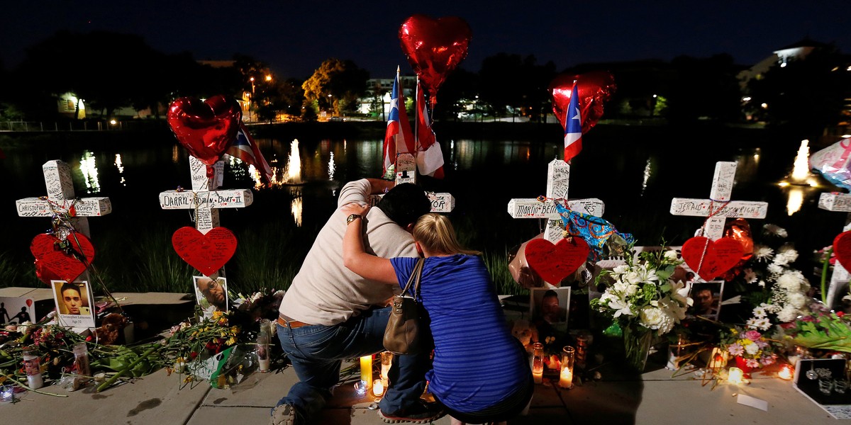 Jose Louis Morales with a woman on Monday at his brother Edward Sotomayor Jr.'s cross, which was part of a makeshift memorial for the victims of the Pulse nightclub shootings in Orlando, Florida.